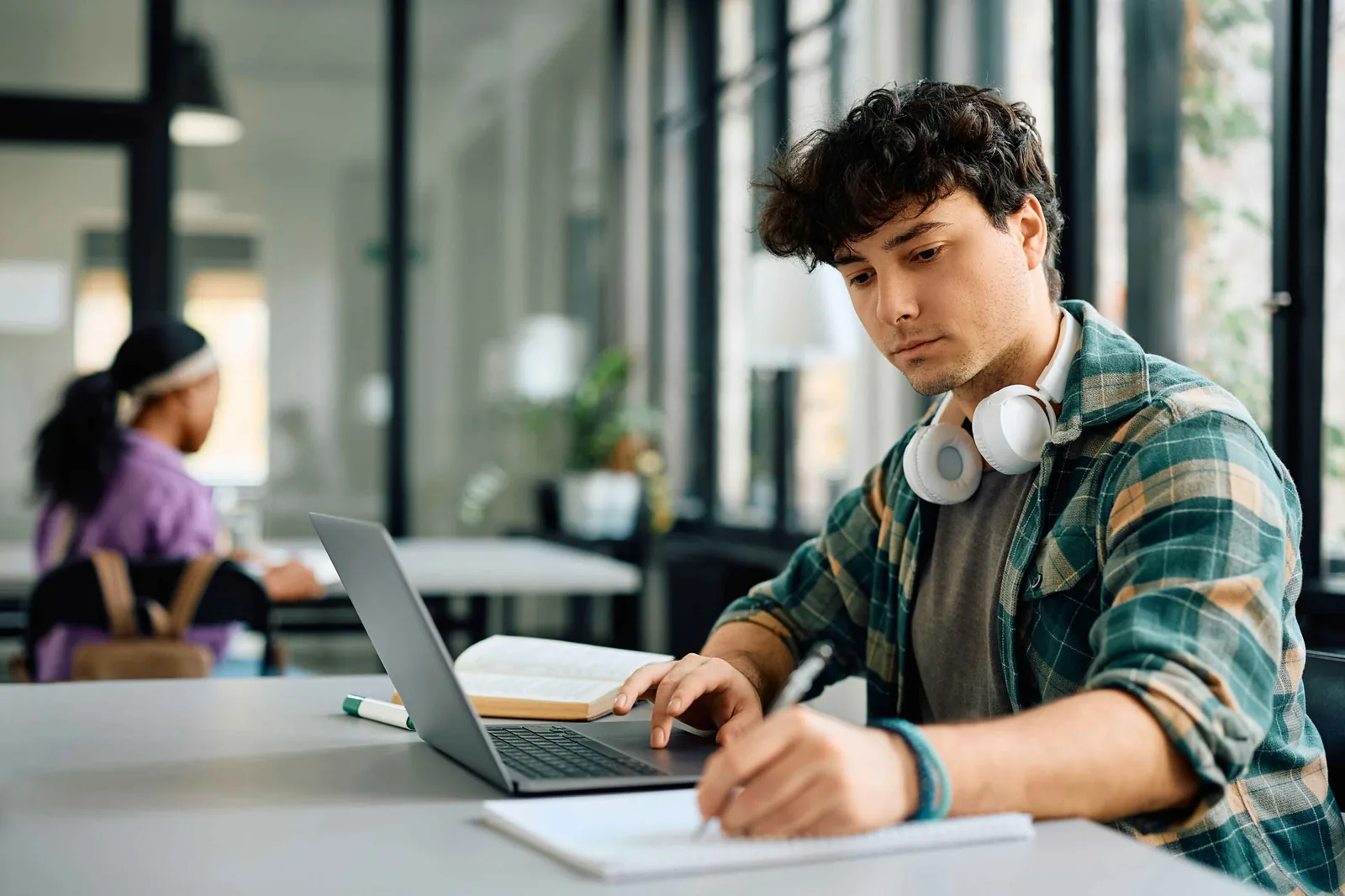 Student arbeitet konzentriert mit Laptop und macht sich Notizen